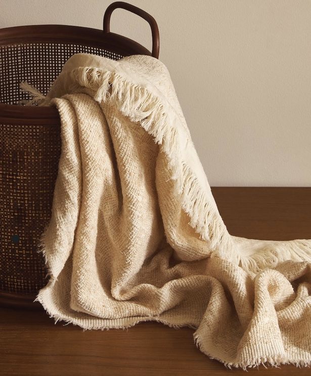Folded throws and decorative cushions arranged in a basket